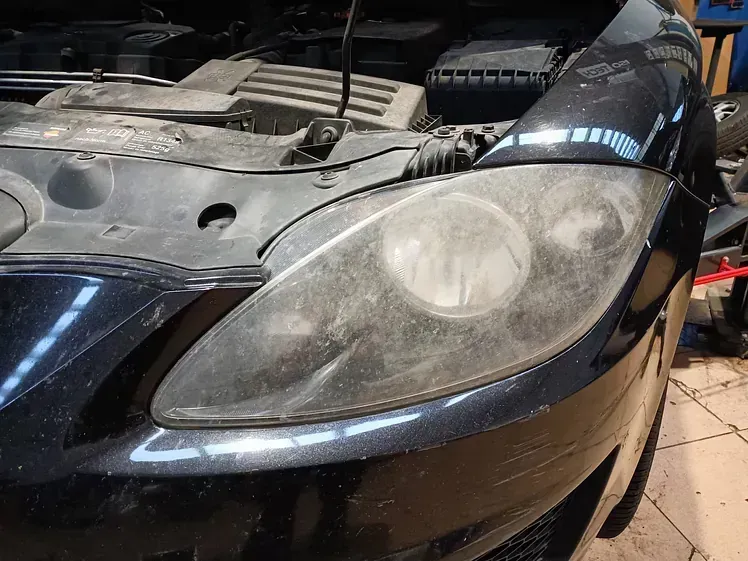 Un coche negro con el capó abierto está estacionado en un garaje.