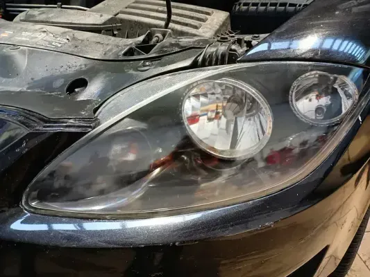 Un primer plano de un faro de coche con el capó abierto.