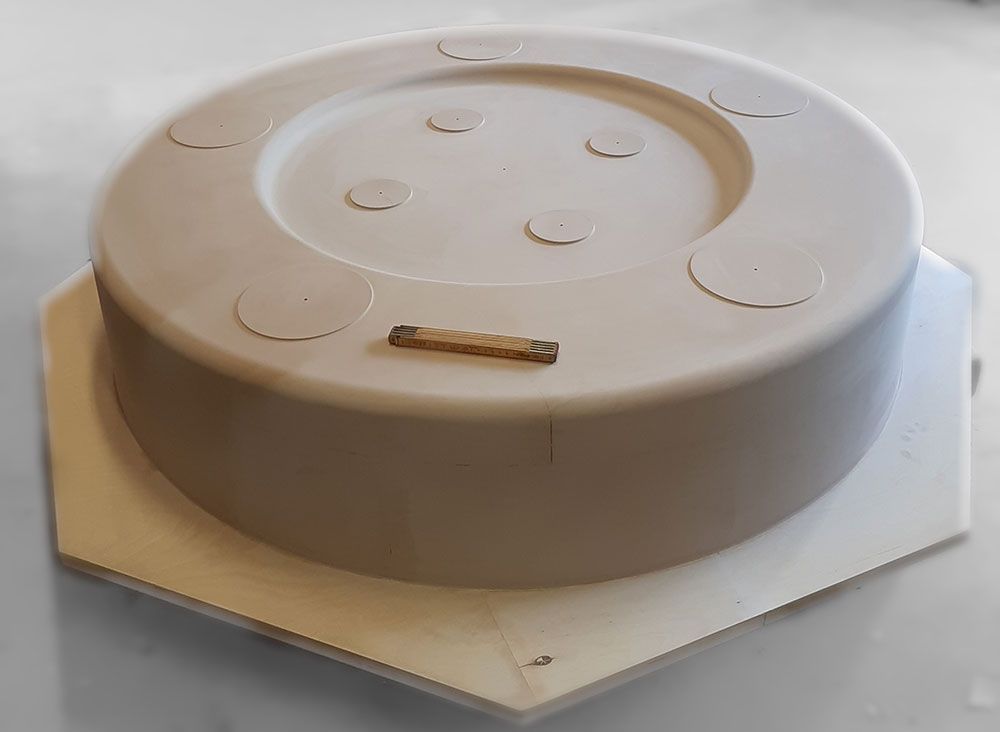 Eine CNC-Maschine schnitzt eine weiße Schaumstoffskulptur mit kreisrunder Oberseite.