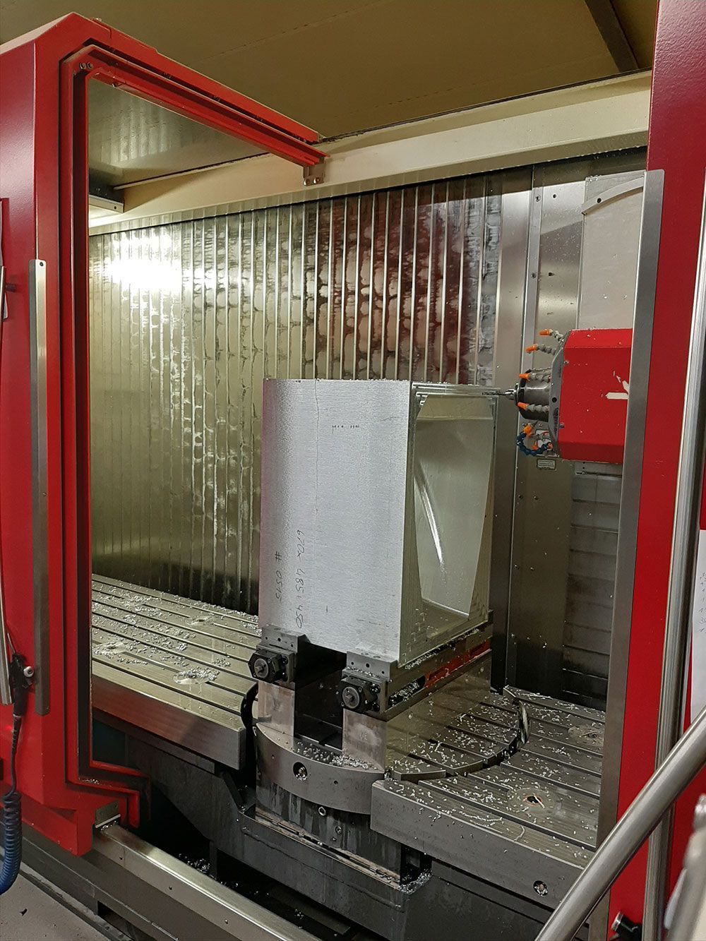 Eine CNC-Maschine schnitzt eine komplexe Form aus orangefarbenem Schaumstoff.