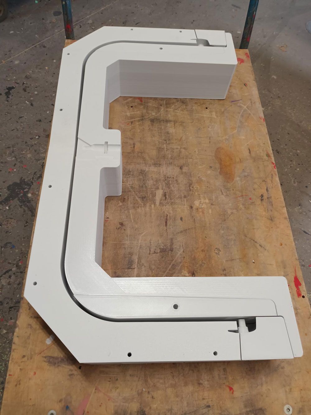 Ein 3D-Druckkopf trägt weißen Kunststoff auf ein teilweise gedrucktes weißes Objekt auf.