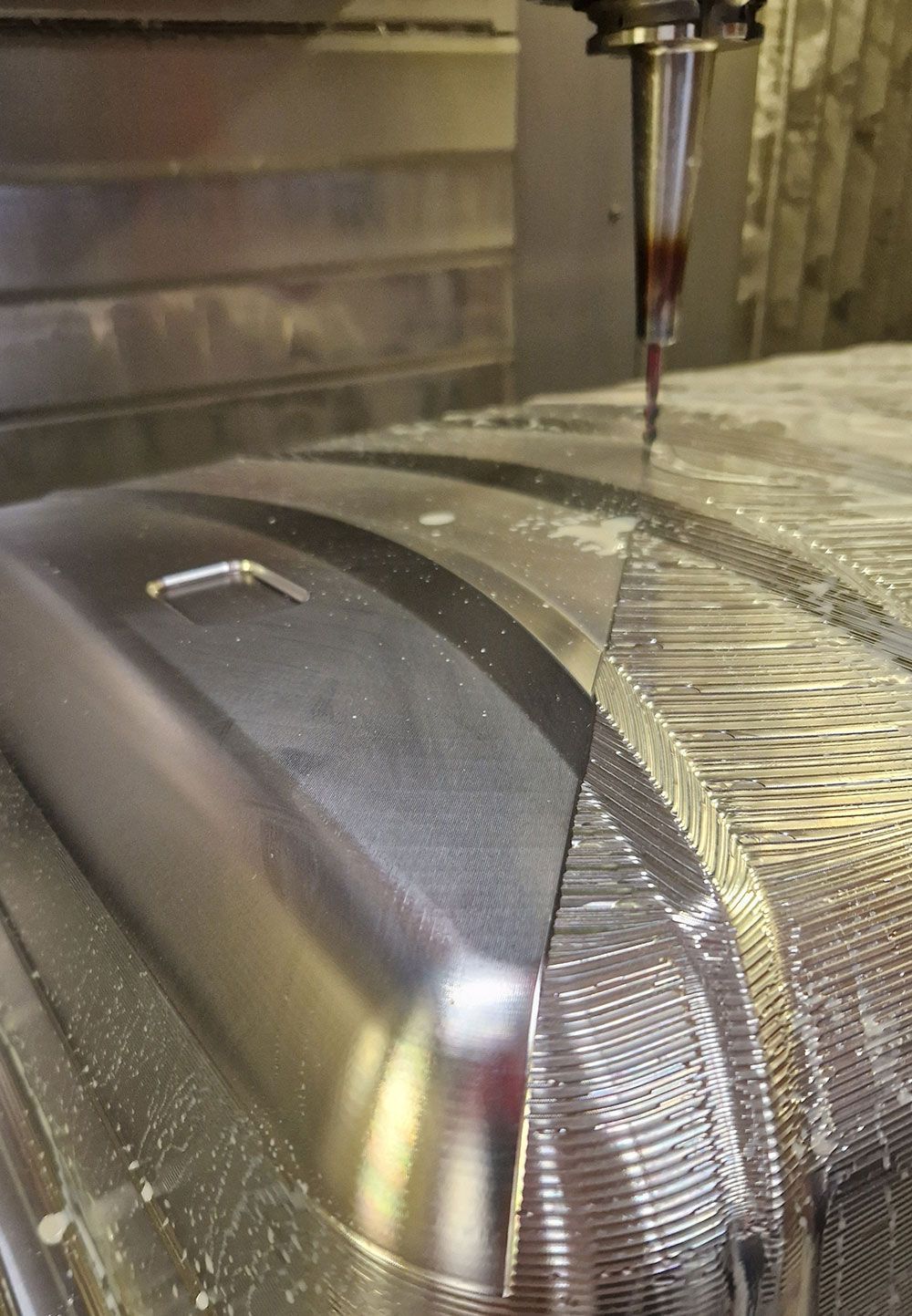 CNC-Maschine fräst Metall und erzeugt mit einem Schneidwerkzeug eine gekrümmte Oberfläche.