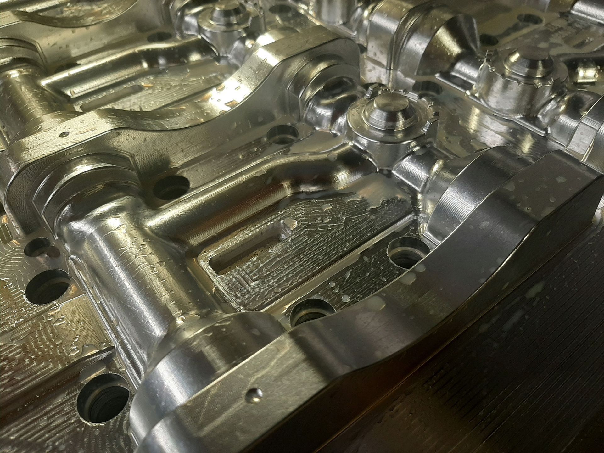 Nahaufnahme eines teilweise bearbeiteten Metallteils mit komplexen Formen und Schraubenköpfen.