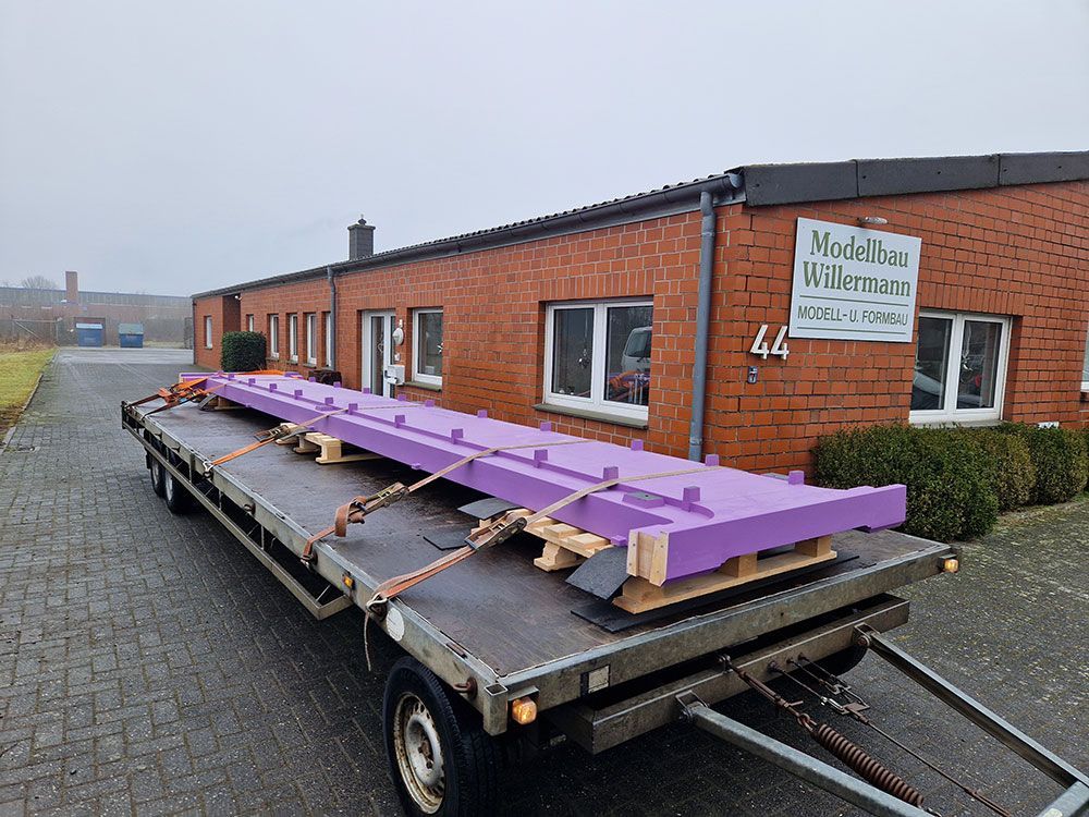 Ein violetter Lichtstrahl ist auf einem Tieflader vor einem Backsteingebäude befestigt.