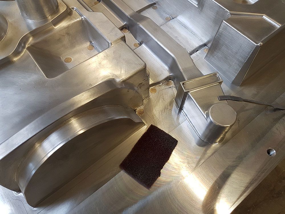 Nahaufnahme einer bearbeiteten Metallform mit einem Schleifklotz.