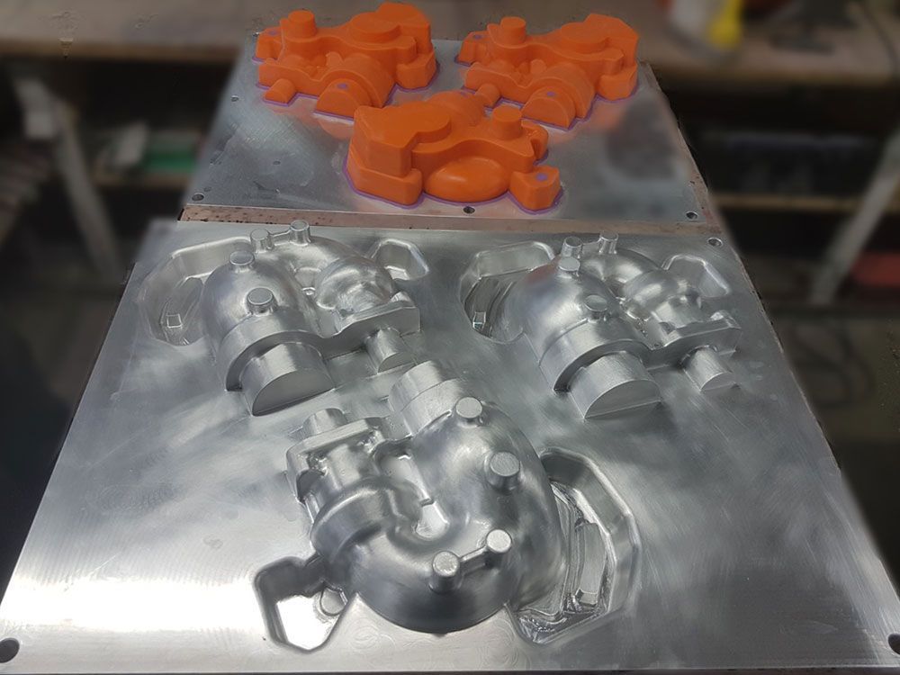 Orangefarbene Kunststoffteile und Aluminiumformen.