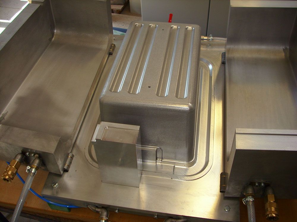 Geöffnete Form, in der sich ein geformter Behälter und Komponenten für die Fertigung befinden.