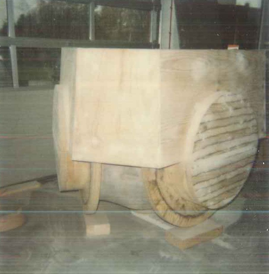 Holzkonstruktion, möglicherweise ein Prototyp, in einem Innenraum. Zylindrische und rechteckige Bauteile.