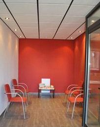 Una sala de espera con paredes rojas y sillas y una mesa.