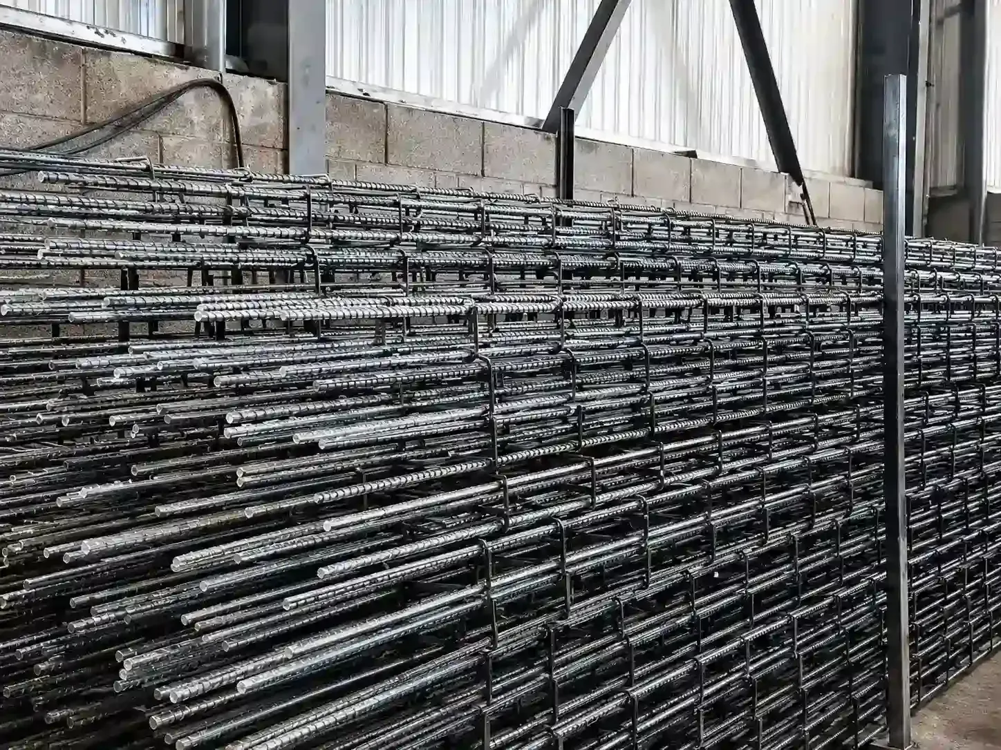 Paneles de malla metálica apilados en un entorno de almacén industrial.