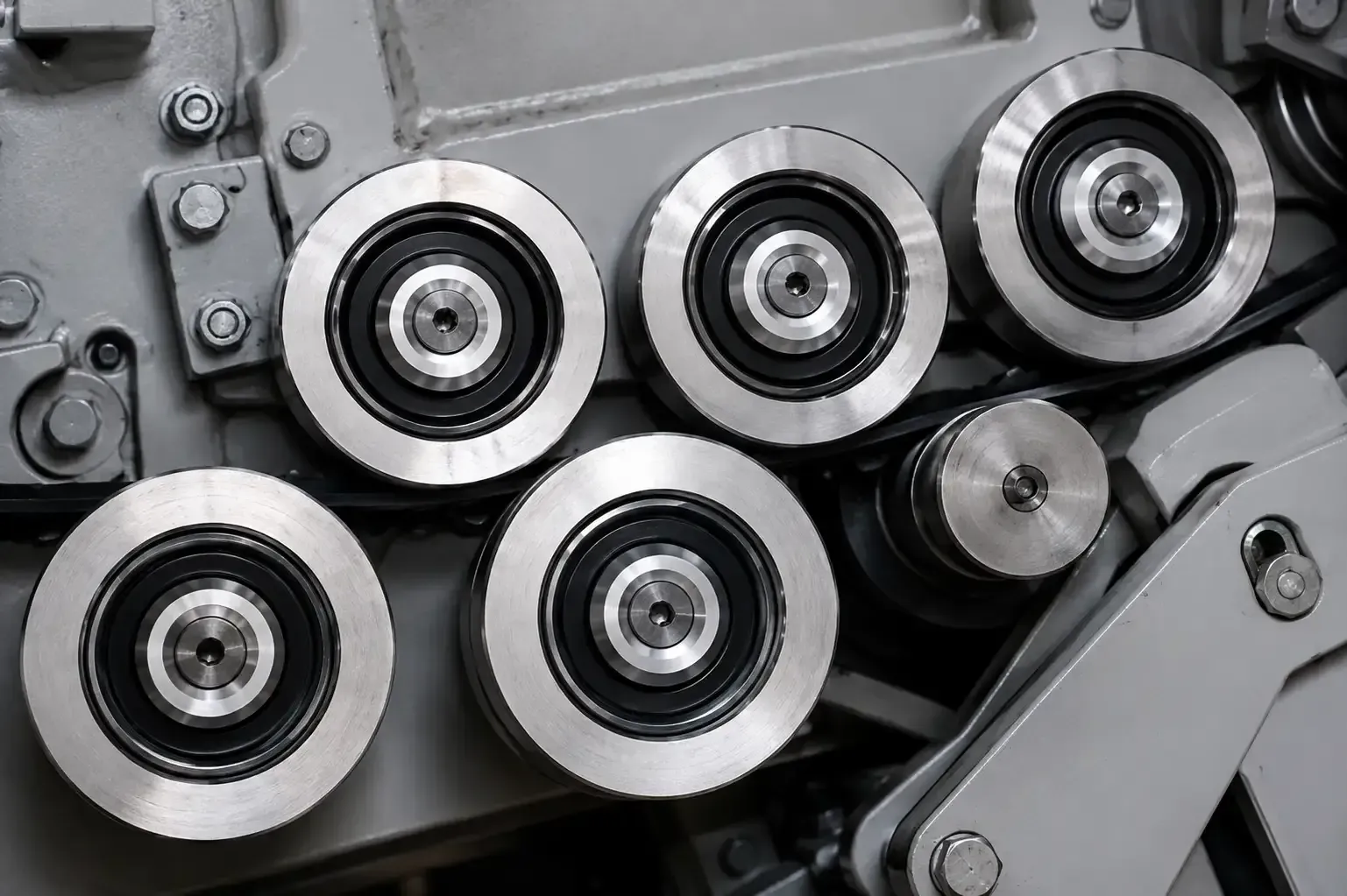 Primer plano de rodillos y engranajes de una máquina industrial de metal gris.