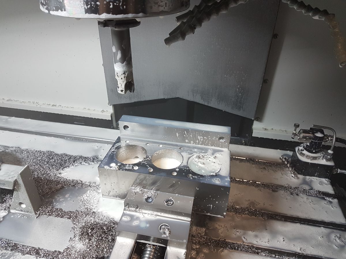 Eine Maschine schneidet ein Stück Metall auf einem Tisch.