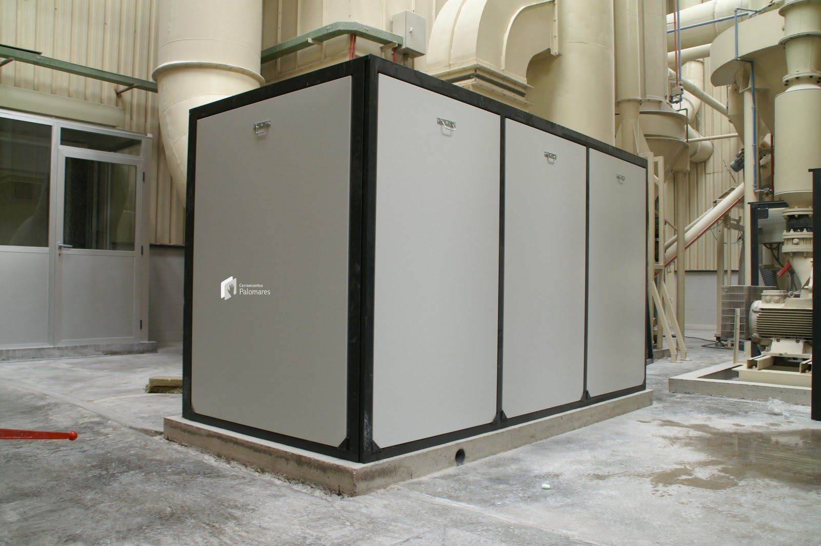 Gran equipo industrial de color gris con detalles en negro, en un entorno de fábrica.