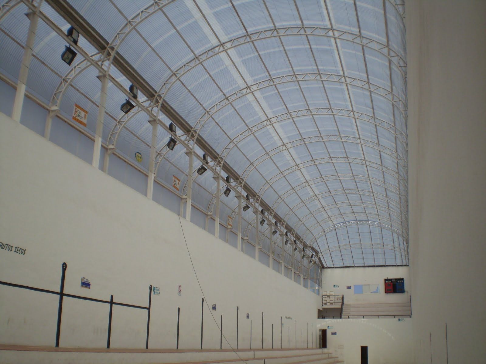 Cancha de balonmano cubierta con techo abovedado transparente y paredes blancas.