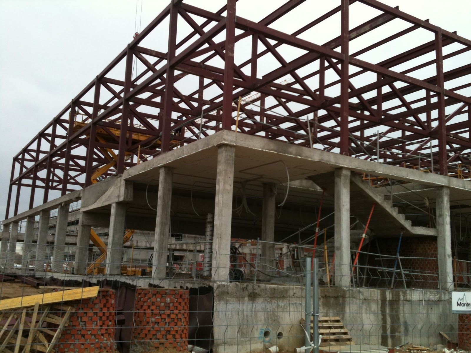 Sitio de construcción: Estructura de acero de un edificio con pilares de hormigón y un tobogán de agua en construcción.