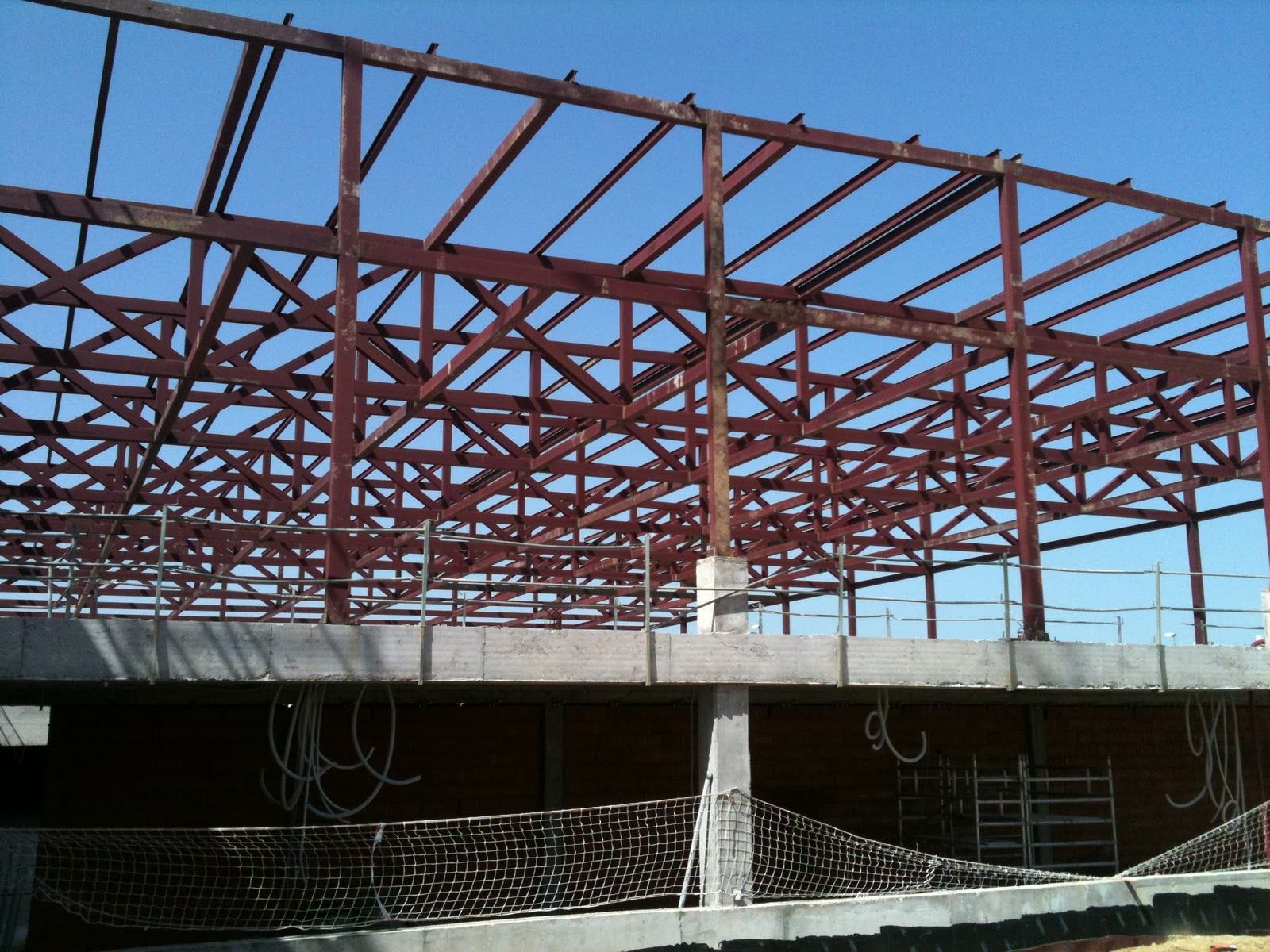 Estructura de acero de un edificio en construcción, contra un cielo azul claro.