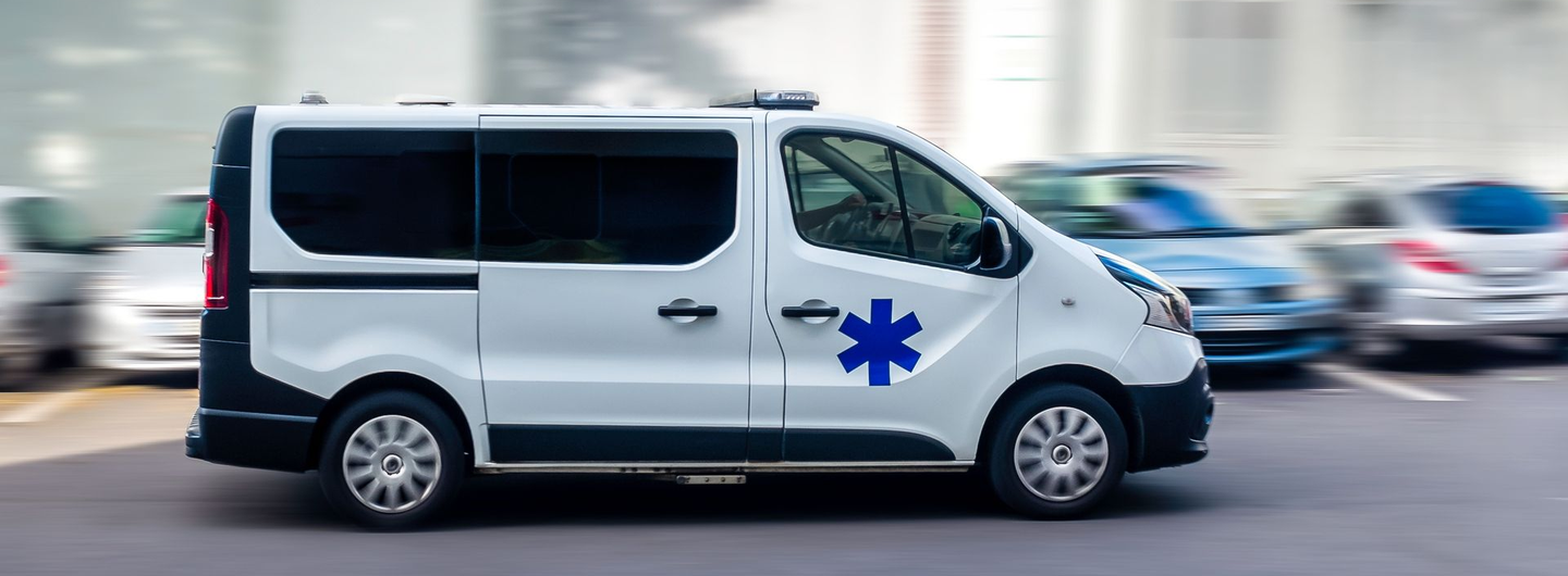 Ambulance blanche avec une étoile bleue, circulant sur une route.