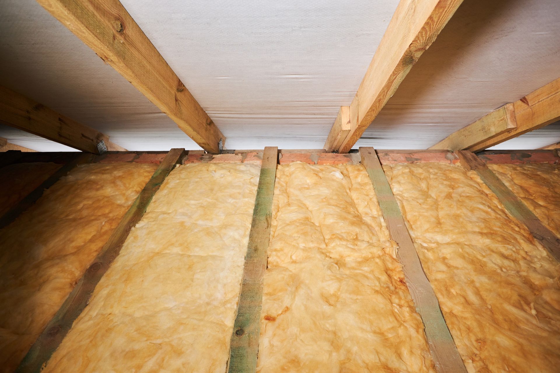 Plafond et combles isolés avec poutres en bois apparentes et laine de verre entre les chevrons