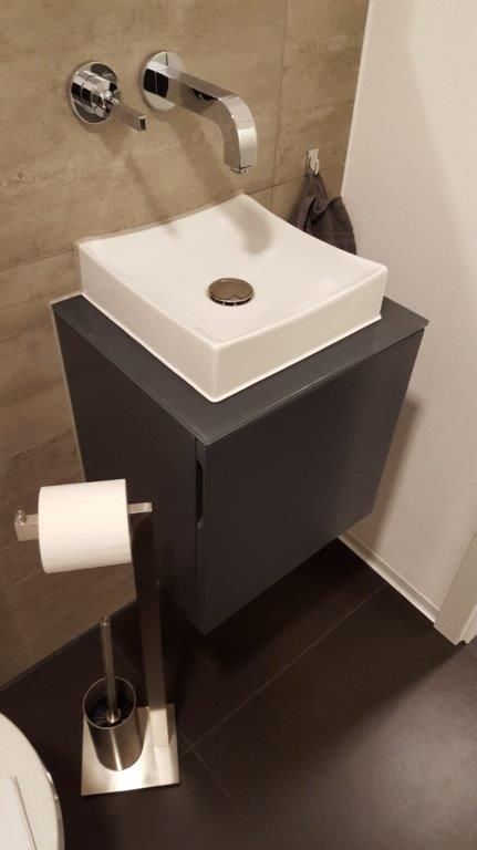 Ein Badezimmer mit Waschbecken, Toilettenpapierhalter und Toilettenbürste.