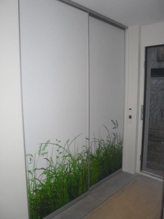 Eine Glasschiebetür mit einem Bild von Gras darauf.