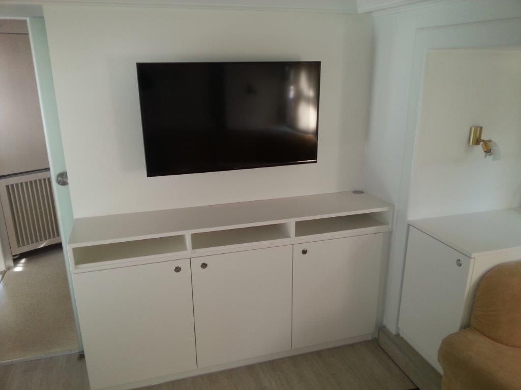 Ein Flachbildfernseher ist an der Wand über einem weißen Schrank montiert