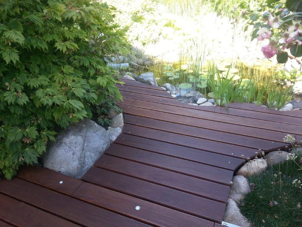 Ein Holzsteg, der zu einem Teich in einem Garten führt