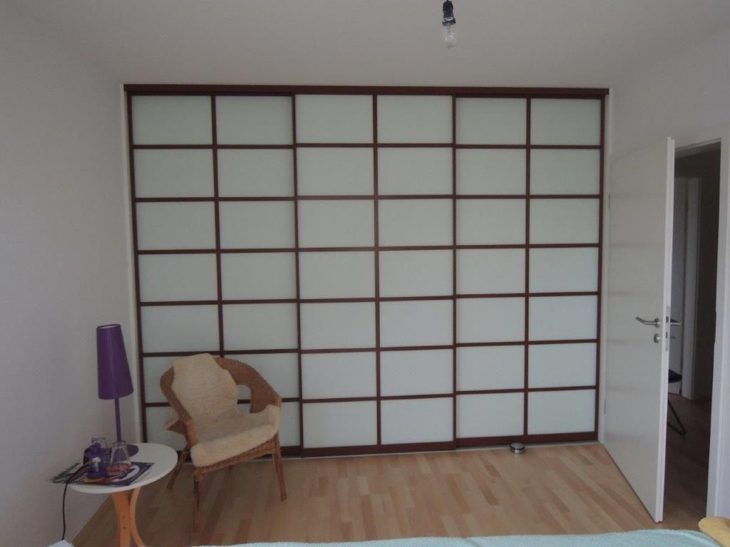 Ein Schlafzimmer mit einer Glasschiebewand und einem Stuhl