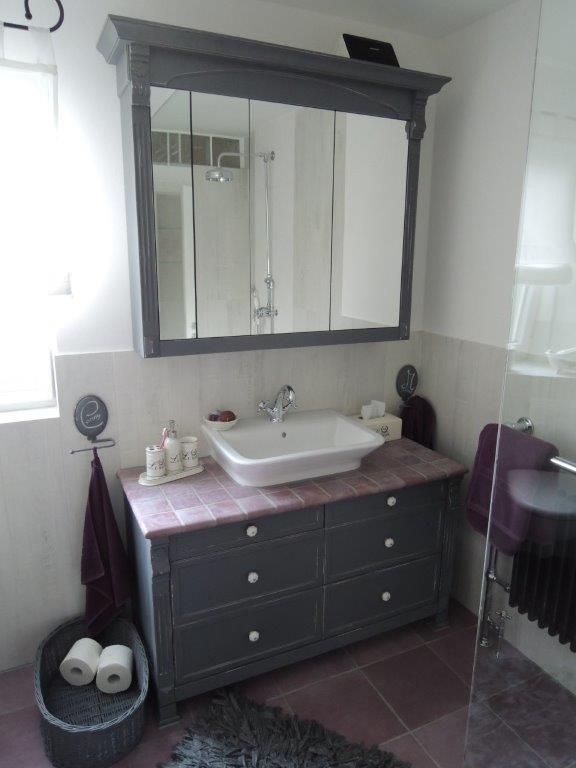 Ein Badezimmer mit einem Waschbecken, einem Spiegel und einem Korb Toilettenpapier