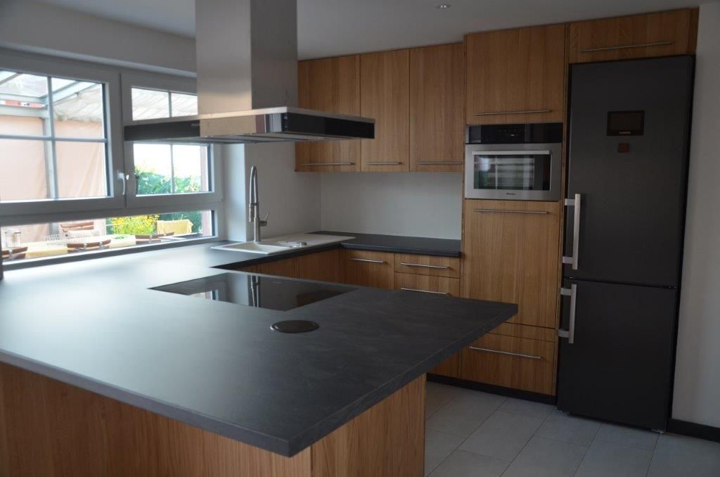 Eine Küche mit Holzschränken und einem schwarzen Kühlschrank