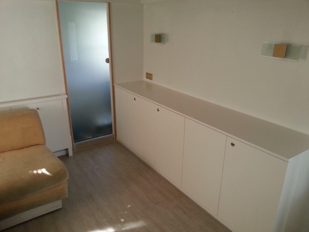 Ein Wohnzimmer mit Couch, Schränken und Glastür.