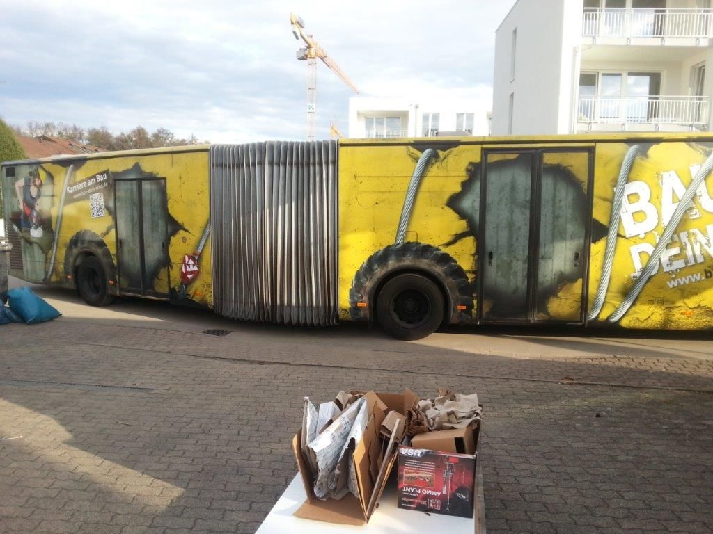 Ein gelber Bus mit Graffiti an der Seite steht auf einem Parkplatz