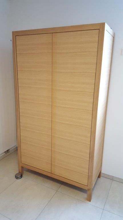 In einem Raum steht ein Holzschrank auf einem gefliesten Boden.
