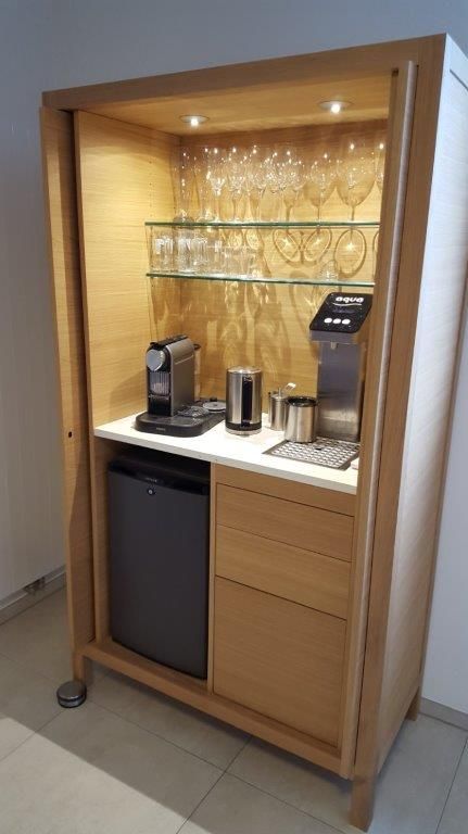 Ein Holzschrank mit Kühlschrank, Kaffeemaschine und Weingläsern.