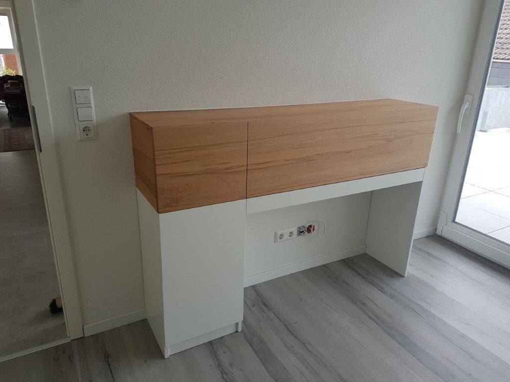 Ein weißer Schreibtisch aus Holz in einem Wohnzimmer neben einer Tür.