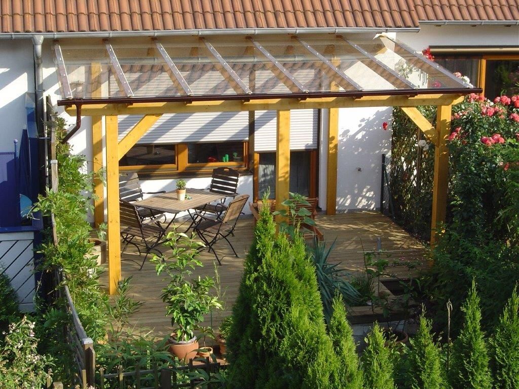 Eine Holzterrasse mit Tisch und Stühlen unter einer Pergola