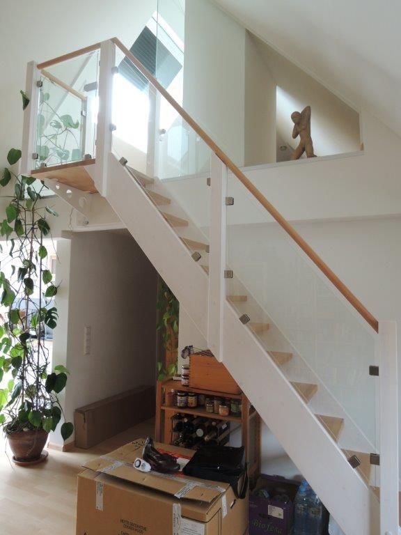 Eine weiße Treppe mit einem Glasgeländer und Kisten darunter