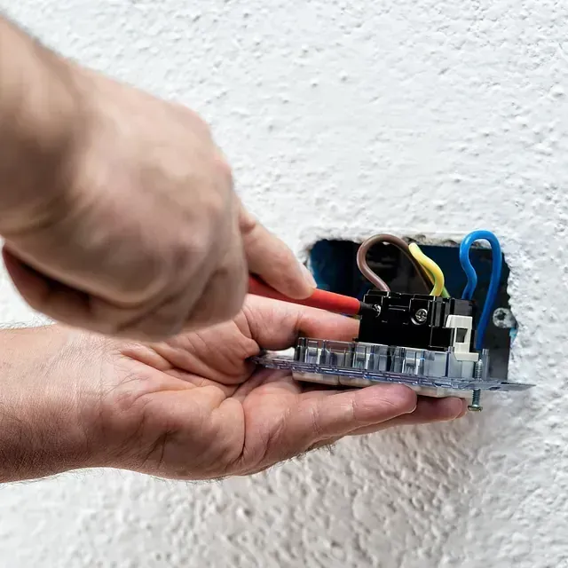 Una persona está instalando una toma de corriente eléctrica en una pared.