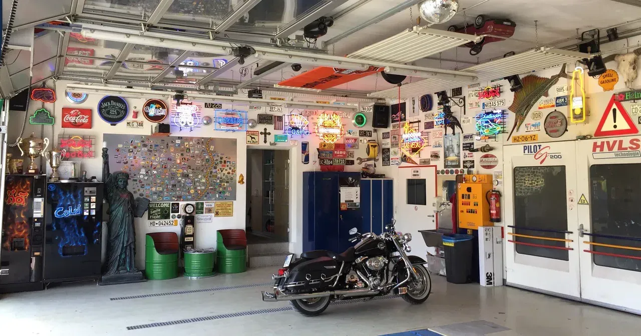 Ein Motorrad ist in einer Garage geparkt, an deren Wänden viele Aufkleber hängen.