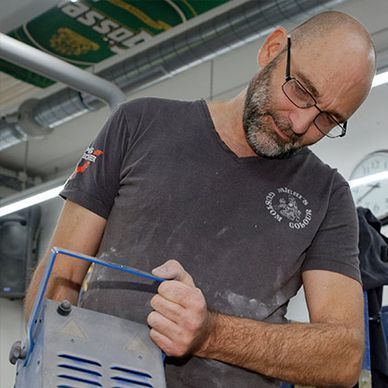 Ein Mann mit Brille und grauem Hemd arbeitet an einer Maschine