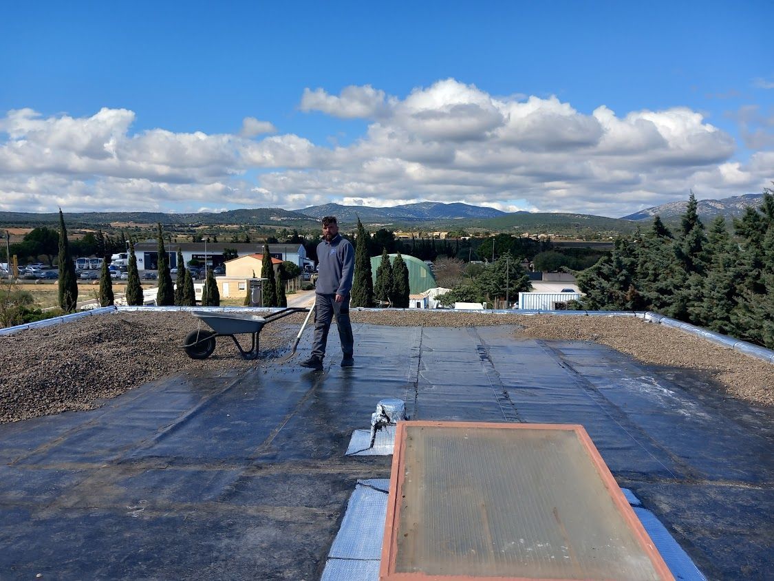 Un employé de SAR Étanchéité pose des graviers sur un toit plat après l'avoir étanchéifié