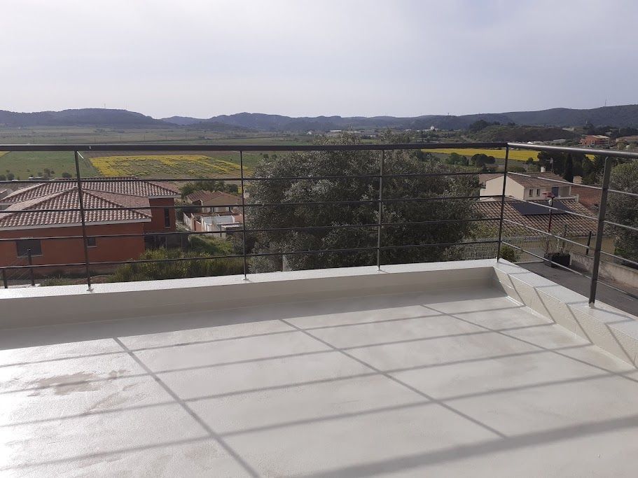 Belle terrasse en hauteur entourée de rembarde avec une belle vue sur des toits de maison plus loin des champs des champs et en arrière plan des montagnes au loin