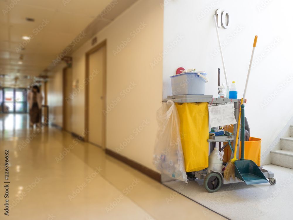 Krankenhausflur mit Reinigungswagen, Wischmopp und gelbem Tuch auf der rechten Seite