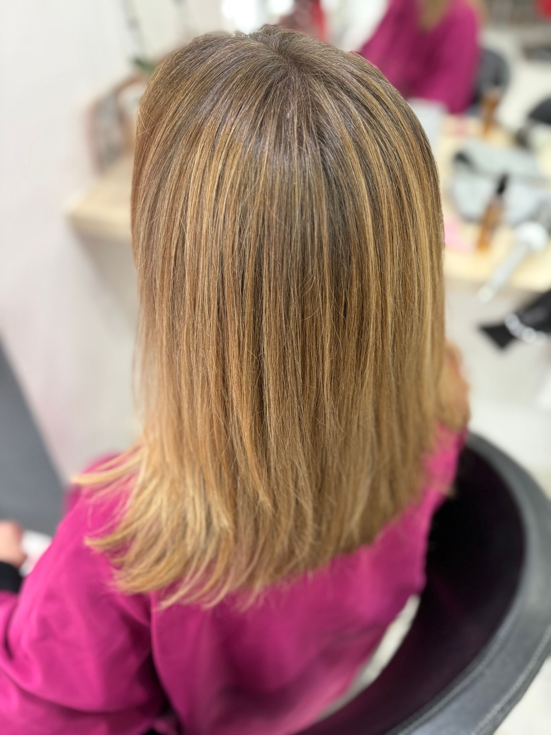 Une personne aux cheveux blonds crêpés assise dans un fauteuil de salon.