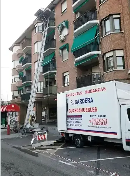 Camión de mudanzas con plataforma extensible descargando muebles en un edificio de viviendas en Madrid.
