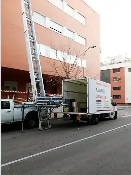 Camión con elevador que ayuda a trasladar mercancías desde un edificio.