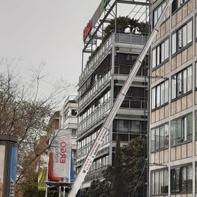 Un edificio con un ascensor elevado al lado, cielo nublado.