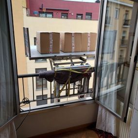 Cajas en una plataforma elevadora frente a la ventana de un apartamento.