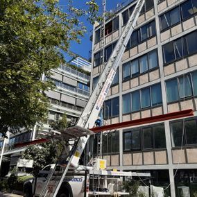 Camión con elevador que se extiende hasta un edificio de varios pisos para mover artículos.