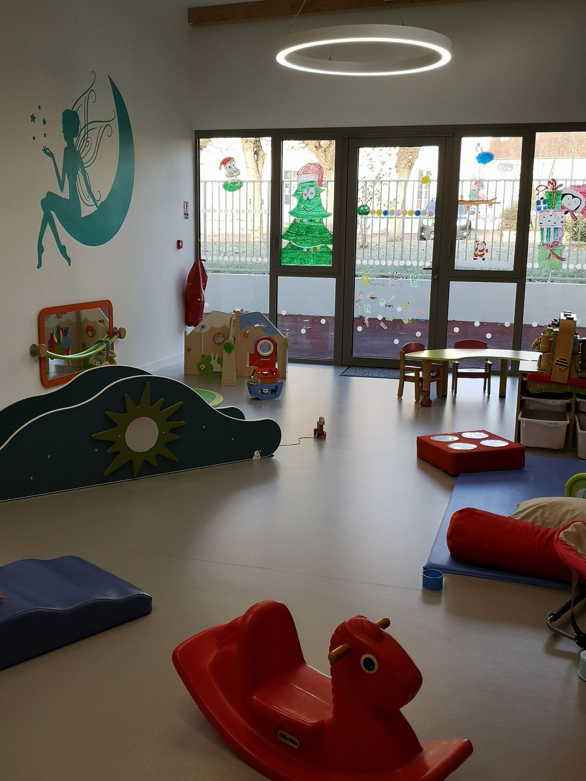 Salle de jeux avec des jouets, dont un cheval à bascule rouge.