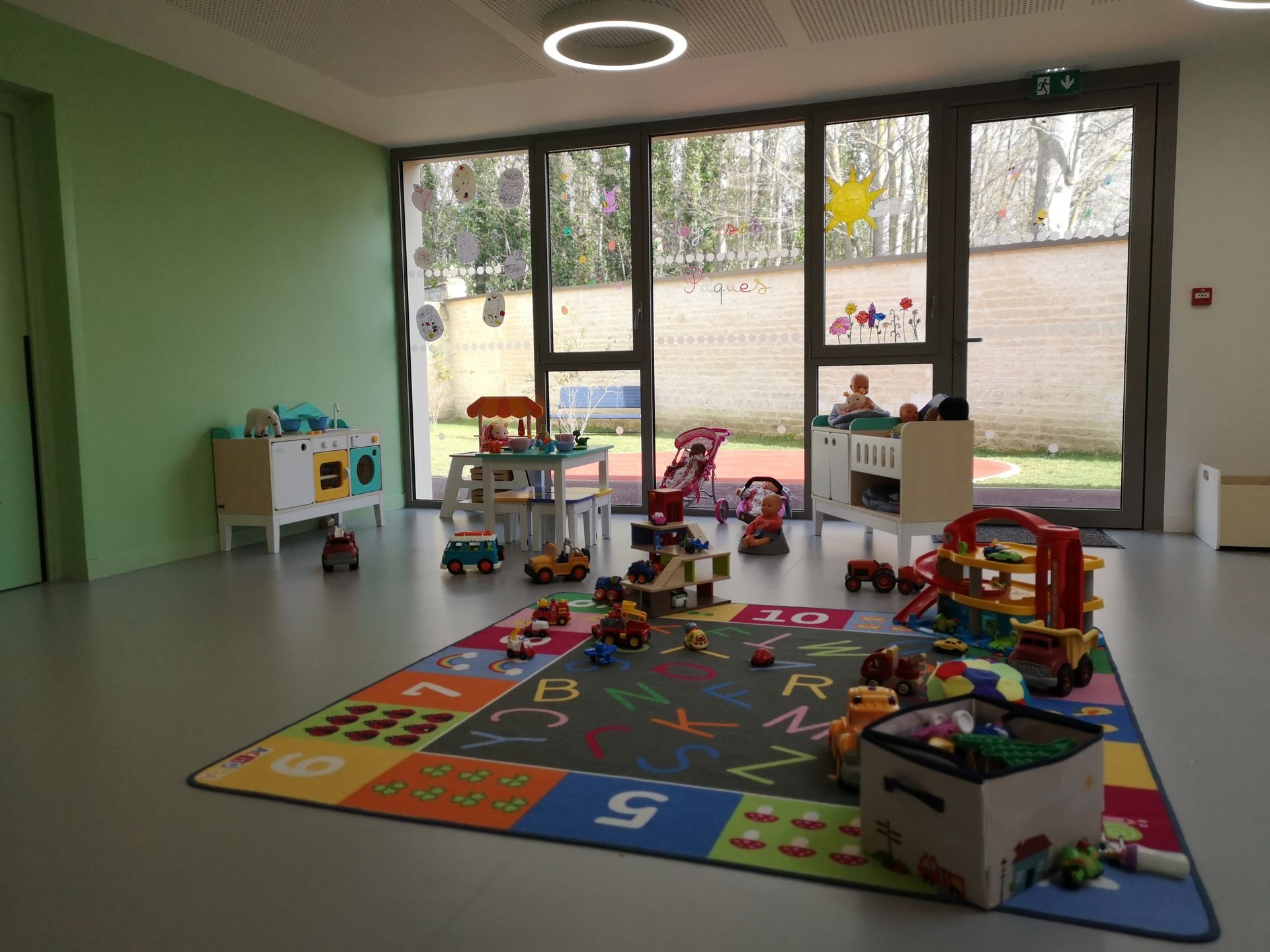 Salle de jeux avec des jouets sur un tapis éveil coloré.